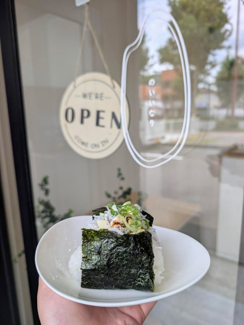 店の入口でおにぎりを手に